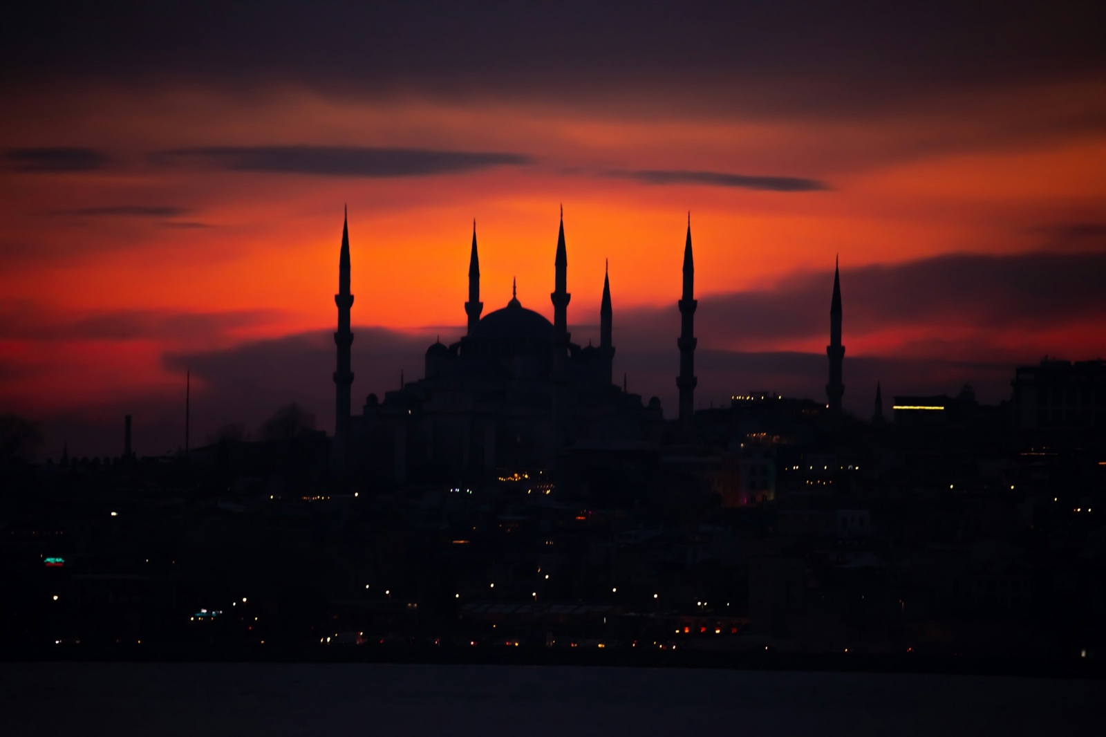 Mosque silhouette against a red and orange sky after sunset.